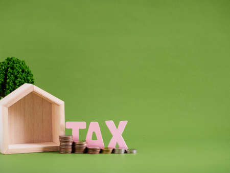 House model with word TAX and coins on green background. Space for textの写真素材