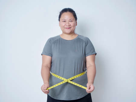 Fat woman measuring waist with tape on white background. Weight loss conceptの写真素材