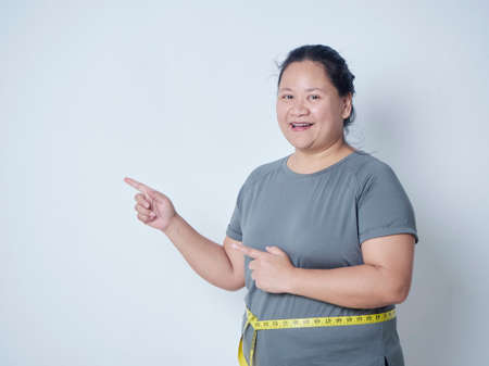 Fat woman measuring waist with tape on white background, space for text. Weight loss conceptの写真素材
