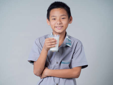 Little boy with glass of milk on gray backgroundの写真素材