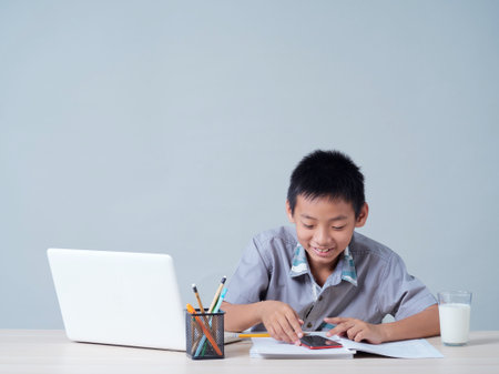 Little boy with laptop studying online at home.の写真素材