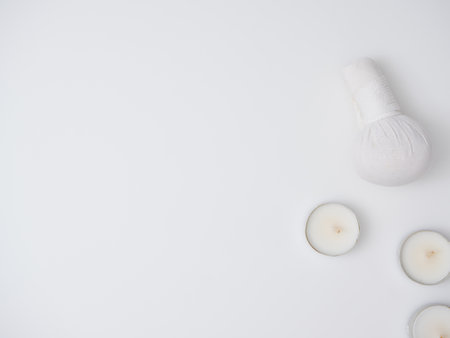 Flat lay composition with herbal compress and other spa products on white background, top view. Space for textの写真素材