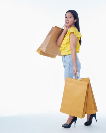 Happy young woman with shopping bags on white background. Space for textの写真素材