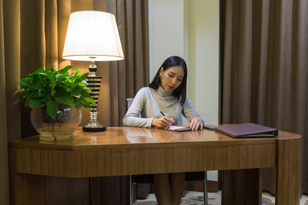 Beautiful asian girl is working on her desk in the private officeの写真素材