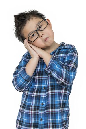 Student boy in glasses feels sleepy on isolated white background with blue shirtの写真素材