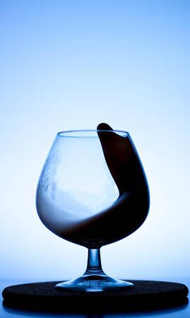 a splash of liquid in a glass wine glass. water pouring inside a glass wine glass. a curl of water in a wine glass. drink in a glass wine glass .splash in the glassの写真素材