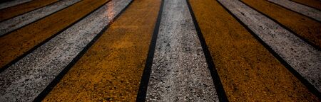 wet from the rain yellow and white pedestrian crosswalk macro photography of a pedestrian crosswalk texture of asphalt and applied yellow and white paint reflections of light on water dropsの写真素材