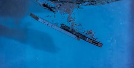 black and white phone dropped into the water. phone in water. blue water. phone in water bubbles.phone sinks in waterの写真素材