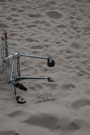 a cart from a supermarket store is lying in the middle of the white sand of the desert. pollution of nature by civilization. destruction of nature. man is littering garbage humanity is pollutingの写真素材