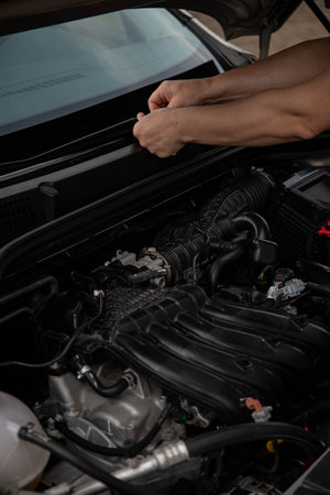 a man repairs a car. a man in blue special clothes to repair the car. engine parts machine repair...