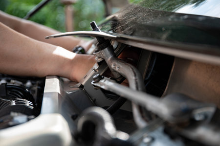 a man repairs a car. a man in blue special clothes to repair the car. engine parts machine repair maintenance breakage problem hands people man masterの写真素材