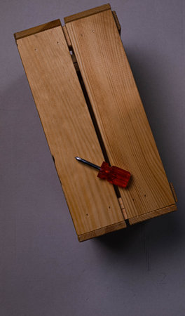 brown wooden box on a white background with a red phillips screwdriver background texture.the...