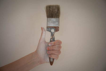 a woman's hand with a paintbrush smeared with paint. a woman paints the walls with white paint. hand smeared in white paint work wall painter paintbrushの写真素材