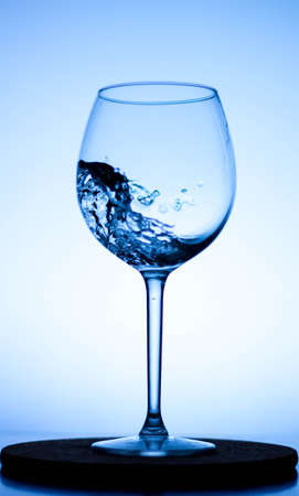 a splash of liquid in a glass wine glass. water pouring inside a glass wine glass. a curl of water in a wine glass. drink in a glass wine glass .splash in the glassの写真素材