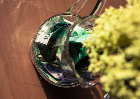 yellow dry flowers in a vase where instead of water of money. flowers grow out of money. vase floor...