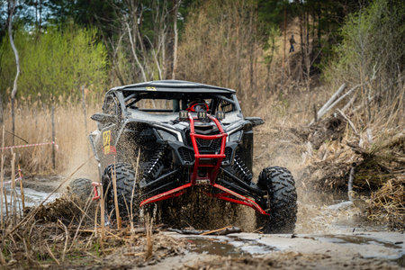 ATV/UTV/4x4 driving throw splashing past a muddy large puddle in forest