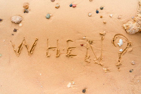 Word "When?" handwritten on the beachの写真素材