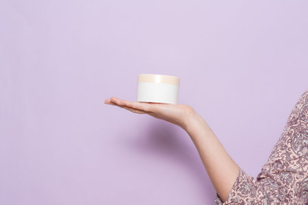 A plastic jar (container) for cream in a woman's hand. Cosmetic product.の写真素材