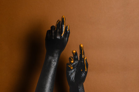Elegant woman's hands with black and gold painted on her skin on a brown background. High Fashion art conceptの写真素材
