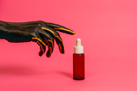 Black and gold painted elegant hand on her skin with a cosmetic unbranded bottle. High Fashion Product cosmetic advertisingの写真素材