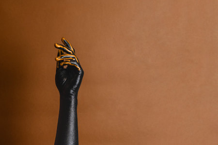 Elegant woman's hands with black and gold painted on her skin on a brown background. High Fashion art conceptの写真素材