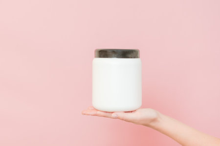 White bottle with nourishing mask for applying to hair or skin in a hand. Beauty and spa, cosmeticsの写真素材