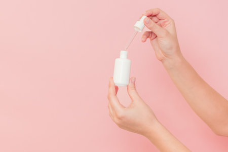 Hand holding glass cosmetic bottle for serum (hyaluronic acid and collagen) on a pink background. Beauty conceptの写真素材