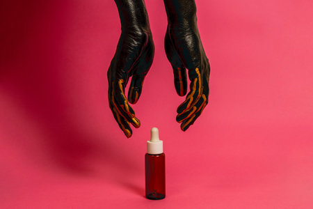 Black and gold painted elegant hand on her skin with a cosmetic unbranded bottle. High Fashion Product cosmetic advertisingの写真素材