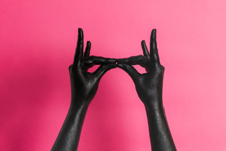 Black painted elegant woman's hands on her skin gesticulate on a pink background. High Fashion art conceptの写真素材