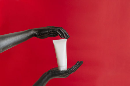 Black painted elegant hands on her skin with a moisturizer cosmetic blank tube. Luxury product cosmetic advertising. Image for your designの写真素材