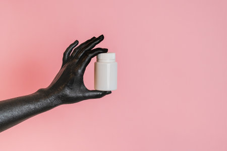 Black painted elegant woman's hand on her skin with a white cosmetic bottle. High Fashion art concept. Product cosmetic advertisingの写真素材
