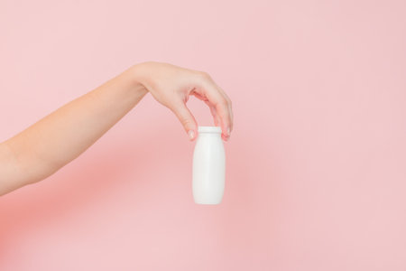 White bottle of probiotic yogurt for digestive system in a hand. Dietary supplements for stomachの写真素材