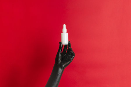 Black painted hand on her skin with a cosmetic glass tube. Luxury product cosmetic advertising. Image for your designの写真素材