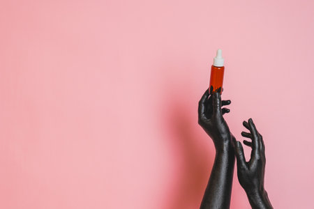 Brown glass bottle with the black painted elegant woman's hands on her skin. Presenting luxury, fashion skincare productsの写真素材