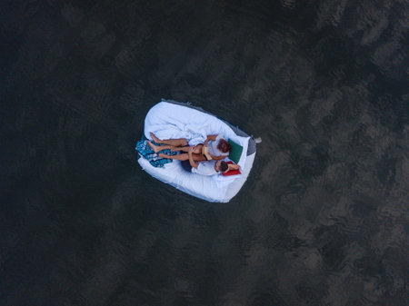 Beautiful couple relaxing together on the bed in lake. Photo from drone