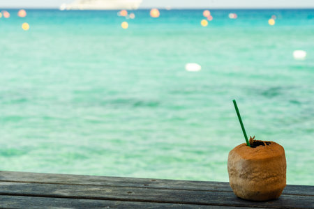 Cocktail in peeled coconut near the crystal blue seaの写真素材