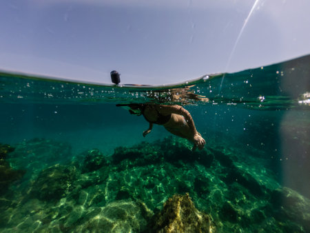 Half above and half below photo of girl snorkelingの写真素材