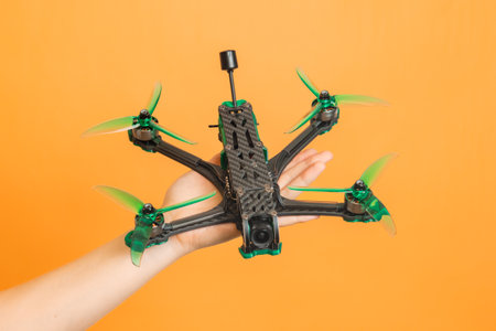 Hands holding a professional modern drone with camera on orange backgroundの写真素材