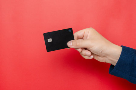 Blank credit card with online service for mockup in businessman's hand on a pink background. Modern way of banking and buying. Business, earning. Space for textの写真素材