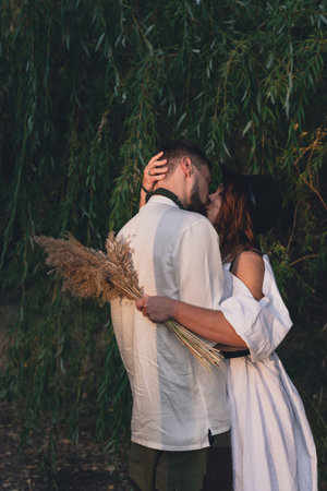 Wedding couple kissing near the willow tree with dried flowersの写真素材