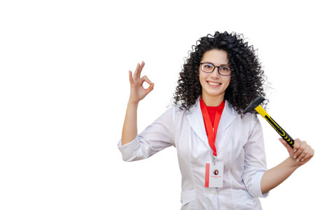 Young brunette woman in white robe holding hammer. Repair conceptの写真素材