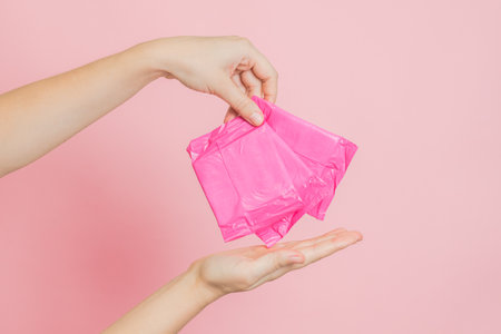 Sanitary pads in hand on a pink background. Concept of menstruation, ovulation, reproduction, pain and personal hygieneの写真素材