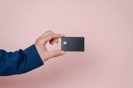 Businessman's hand with blank credit card with online service for mockup on a pink background. Modern way of banking and buying. Business, earning. Space for textの写真素材