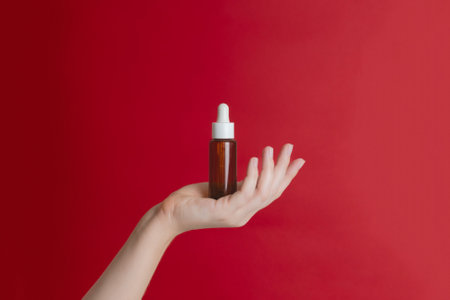 Serum glass unbranded bottle (essential oil) with pipette on a red background. Natural moisturizing,...