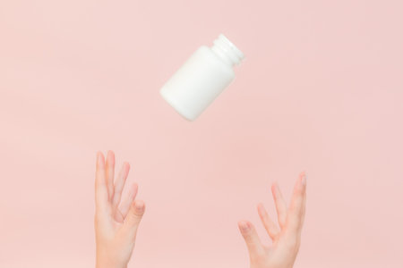 Female hand holding a cosmetic container for cream, vitamins, pills. Cosmetic beauty packagingの写真素材