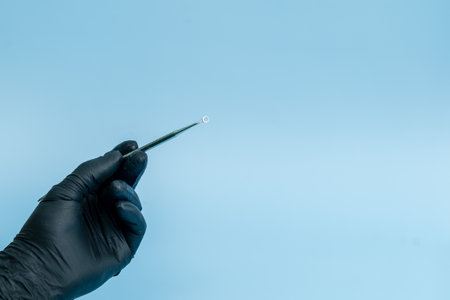 Cropped shot of professional dentist in black medical gloves with dental tool. Dental concept. Isolated on blue backgroundの写真素材