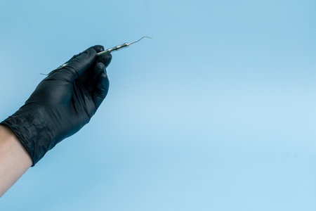 Cropped shot of professional dentist in black medical gloves with dental tool. Dental concept....