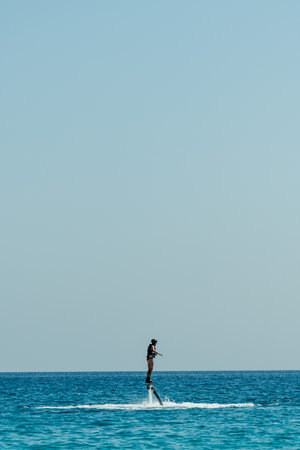 Man trying stand on flyboard. Water extreme sports.