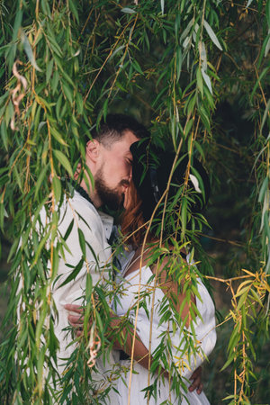 Wedding couple kissing near the willow tree