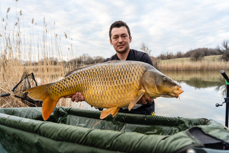 Fisherman holding a huge carp at the lake.の写真素材